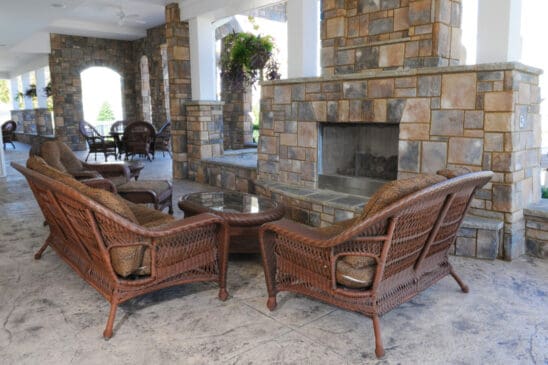Covered patio with stone fireplace and wicker seating