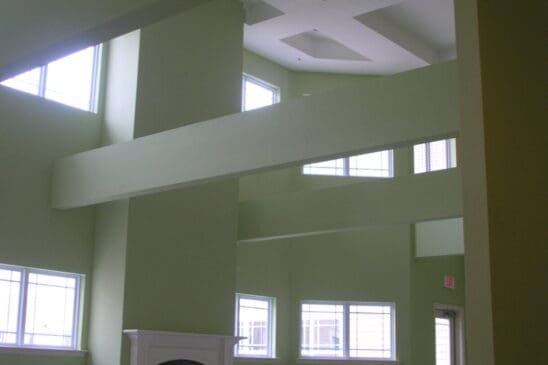 Tall green living room with high windows and fireplace