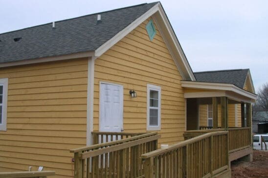 Yellow single-story house with wooden ramp and porch