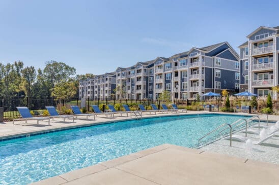 Modern apartment complex with outdoor pool and loungers