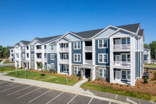 Modern three-story apartment building with balconies and parking lot