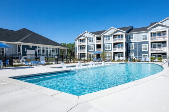 Modern apartment complex with outdoor swimming pool and lounge chairs