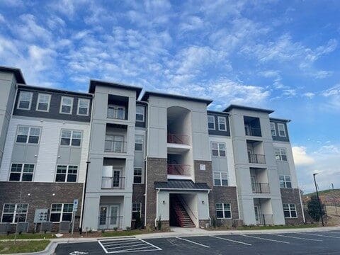 Modern four-story apartment building with parking lot