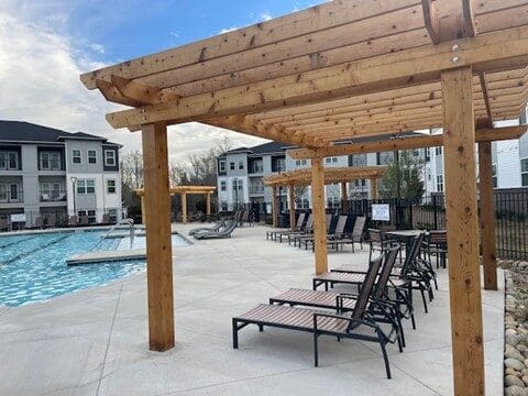 Apartment pool area with wooden pergolas and lounge chairs