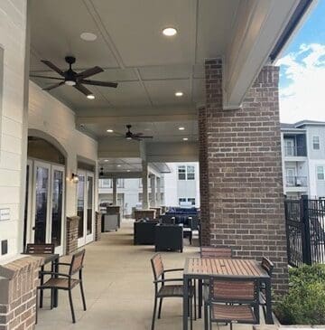 Covered outdoor patio with tables, chairs, ceiling fans