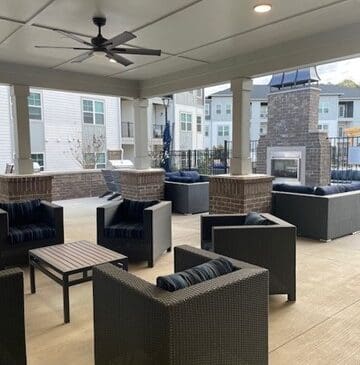 Covered outdoor patio with wicker seating and fireplace