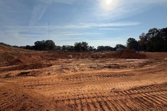 Dirt construction site with tire tracks under sunny sky