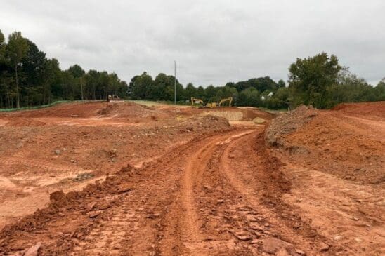Muddy construction site with dirt road and excavators