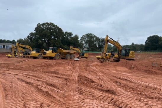 Excavators and dump trucks on dirt construction site