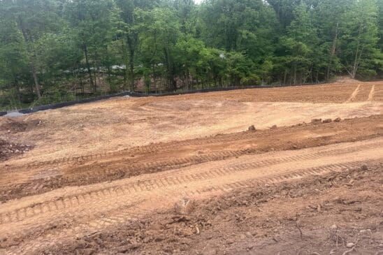 Graded dirt construction site beside wooded area