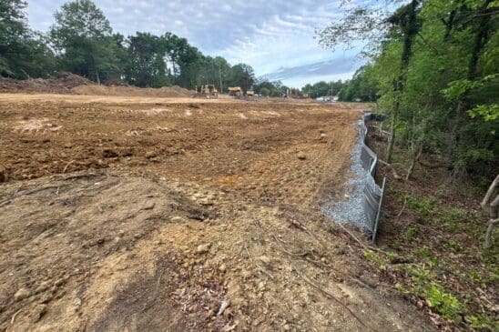 Cleared construction site with bulldozers and silt fence